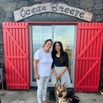 Vibrant red shutters frame sliding glass doors, crowned by a curving sign reading, &ldquo;Ocean Breeze.&rdquo; Dalila and I stand smiling in front of the doors, and Mylo is sitting beside us.