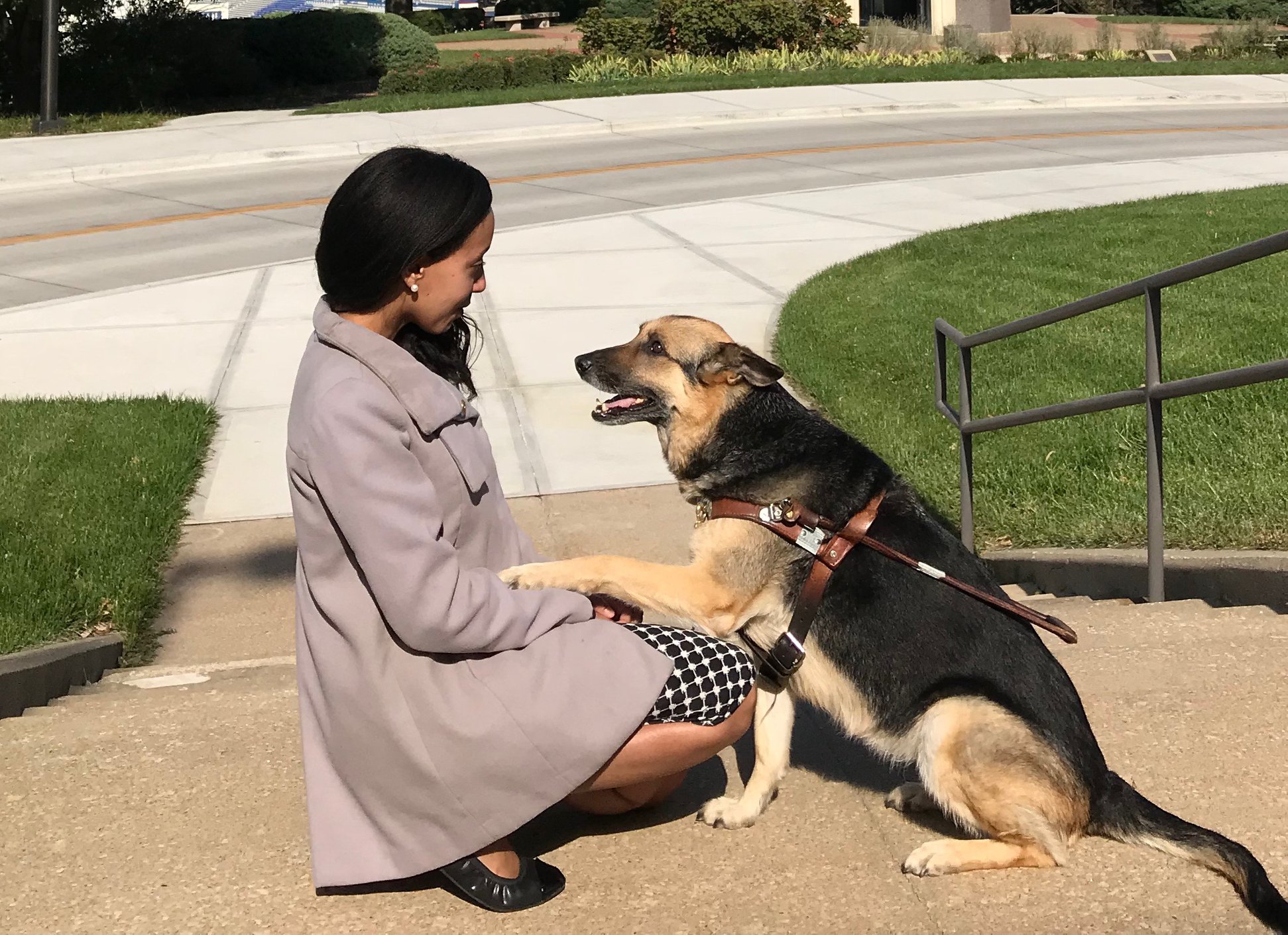 Maxine is looking up at Haben with her paw on Haben's arm. Haben is kneeling beside Maxine