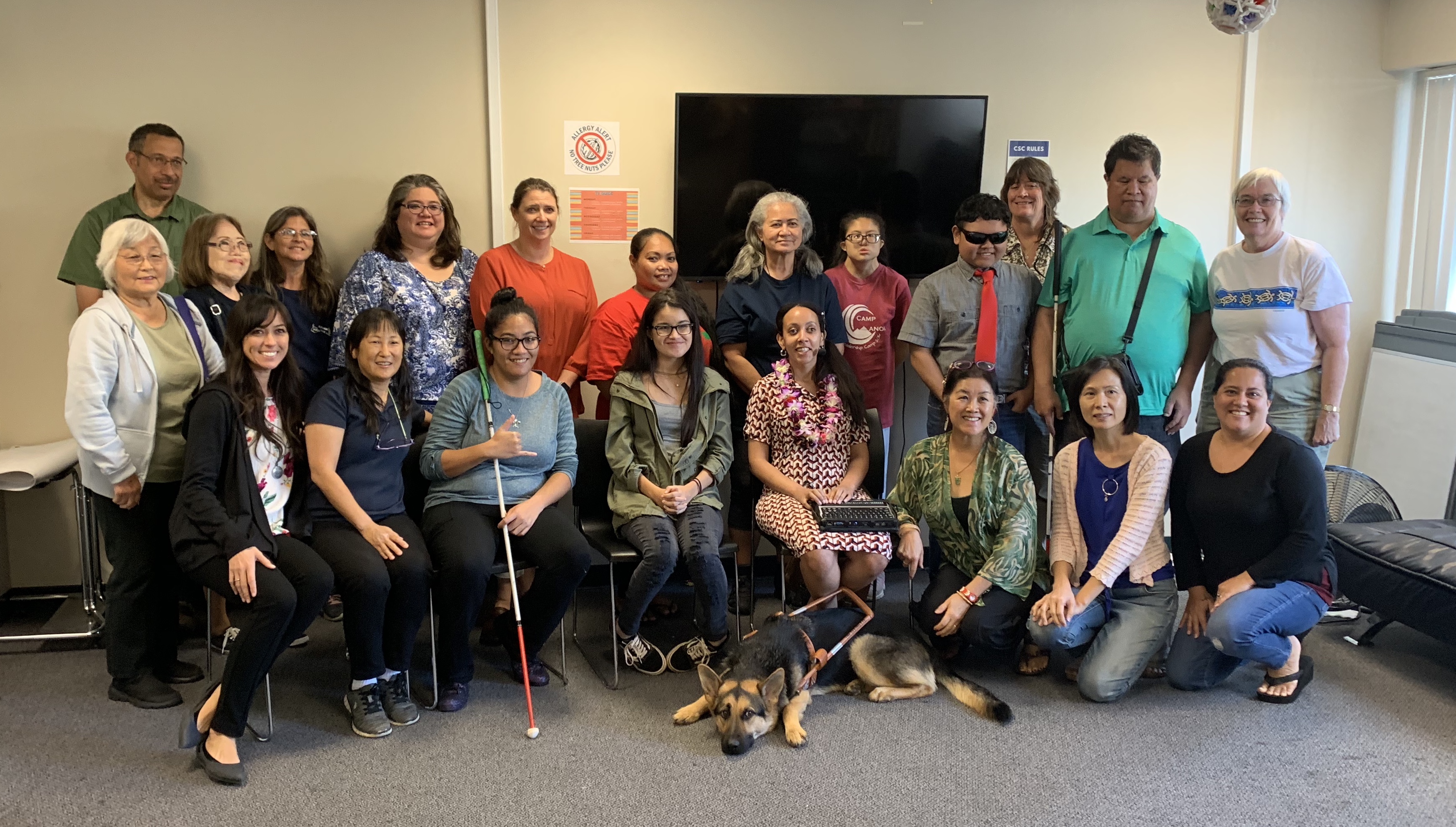 Twenty members of the Hawaii Deafblind community, from high school students to grandparents, stand together. Haben is wearing two leis gifted to her by the kupuna, the elders. One has smooth kukui nuts, the other has orchids, carnations, and tuberoses that smell AMAZING! Mylo, Haben’s Seeing Eye dog, is stretched out on the floor in front of Haben