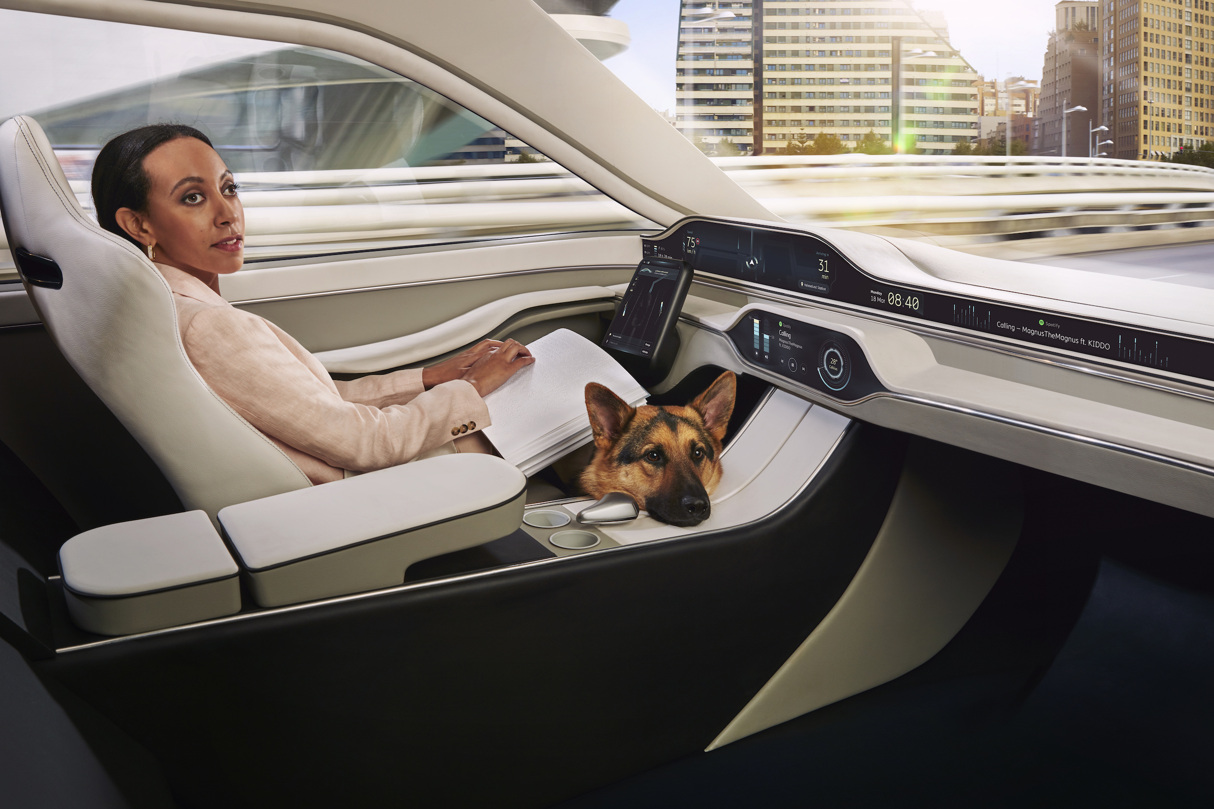 Haben is casually reading a page of braille in the driver’s seat of a car. The driver’s seat doesn’t have a steering wheel, just a touchscreen tablet. In the film Haben controls the tablet with her braille computer. An adorable German Shepherd dog is on the floor, his head peaking up over the central panel.